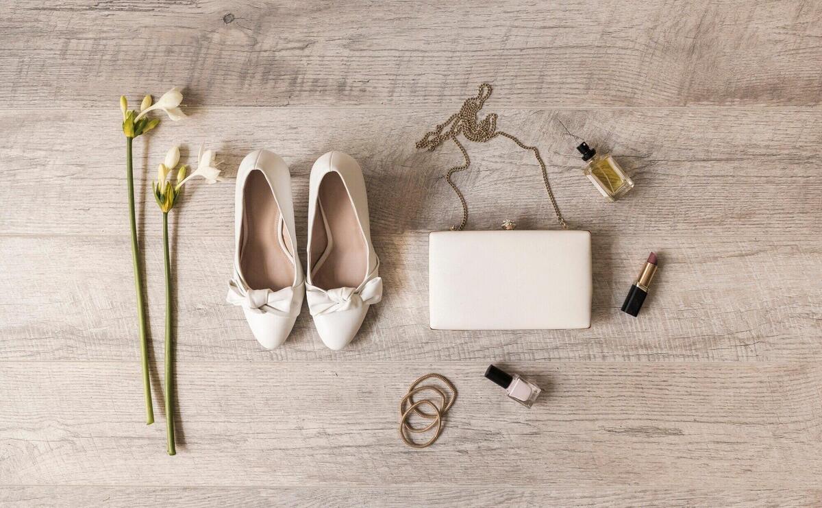 Flowers; dress shoes; clutch; perfume; lipstick; nail varnish and hairbands on wooden backdrop