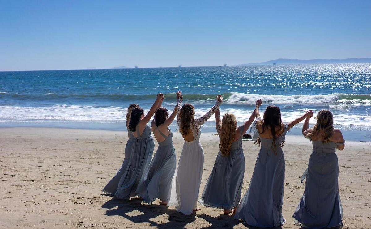 women in white dresses standing on brown sand near body of water during daytime