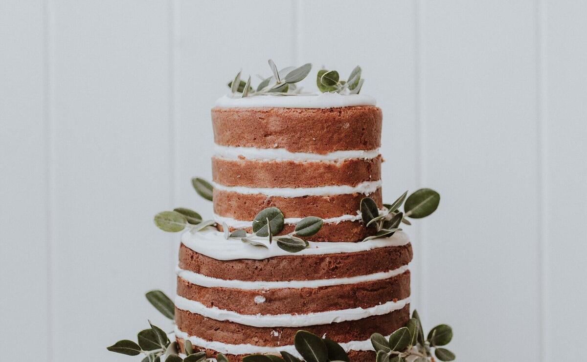 Beautiful rustic wedding cake decorated with eucalyptus on white wooden background