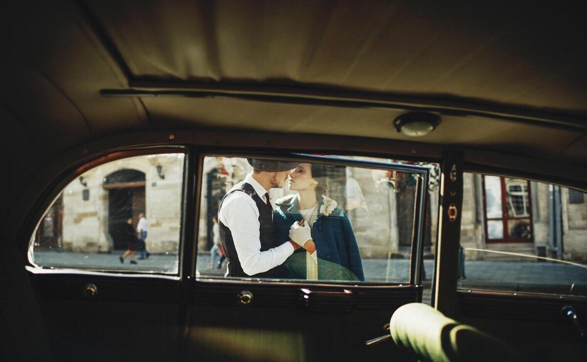 Look through the retro-car at a man and woman dressed in old-fashion style